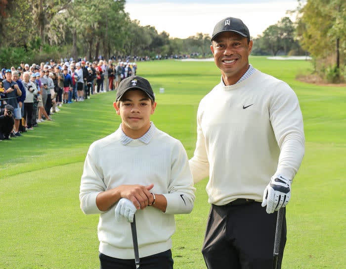Tiger Woods standing with his son Charlie on a golf course