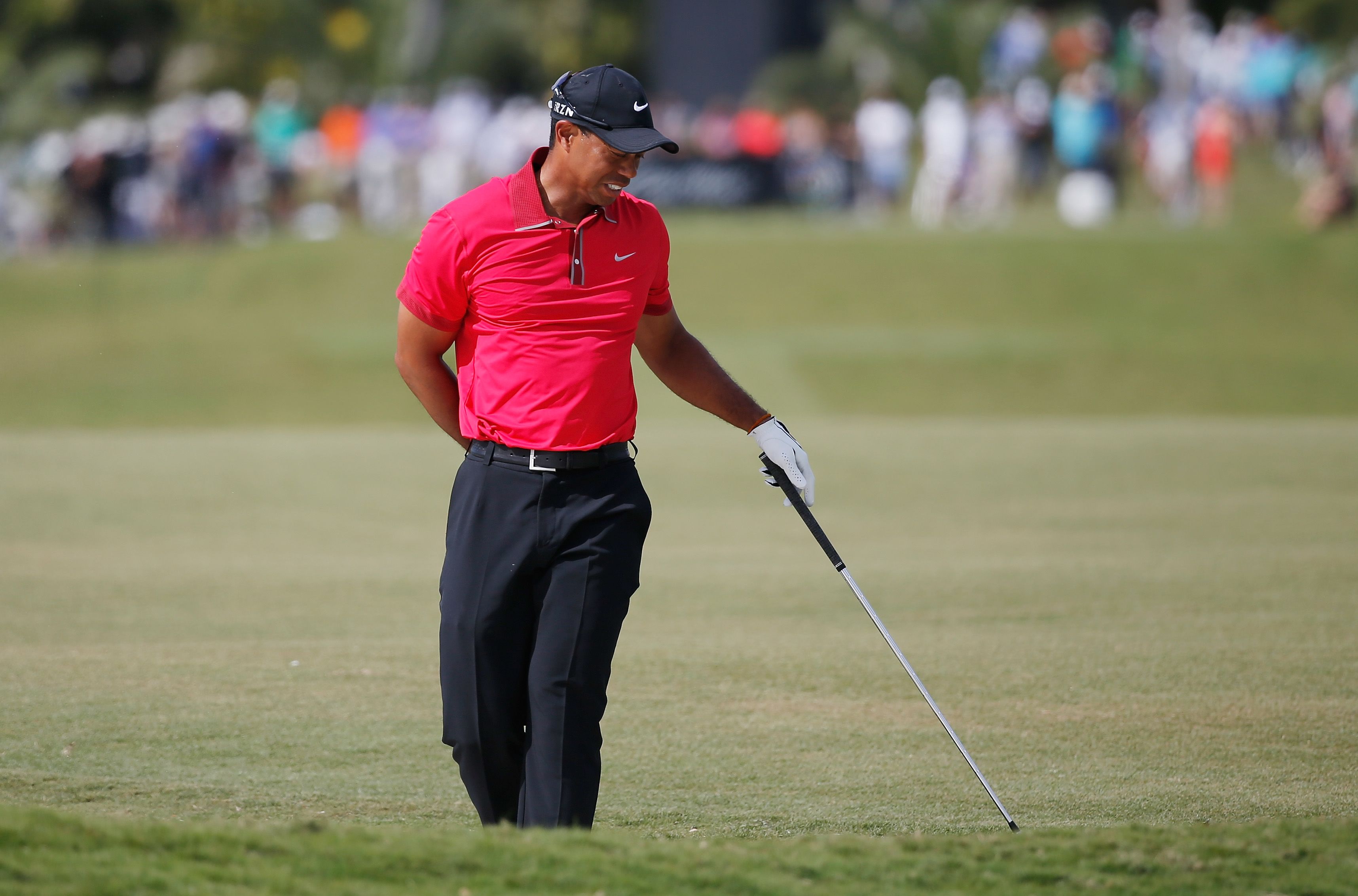 Tiger Woods follows through on a driver swing in his signature red Sunday shirt